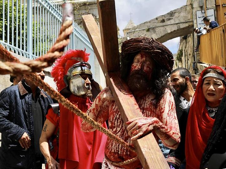 Gläubige stellen in der Via Dolorosa in Jerusalems Altstadt den Kreuzweg nach. Ein Jesus-Darsteller trägt ein hölzernes Kreuz durch die Straßen.
