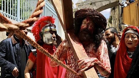 Gläubige stellen in der Via Dolorosa in Jerusalems Altstadt den Kreuzweg nach. Ein Jesus-Darsteller trägt ein hölzernes Kreuz durch die Straßen.