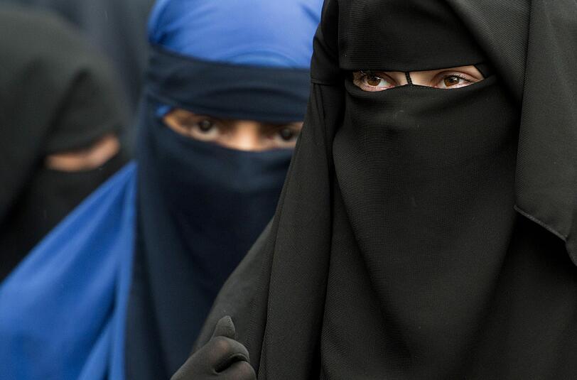 Verschleierte Frauen schauen durch die Schlitze ihrer Nikab. Foto: Boris Roessler/Archiv