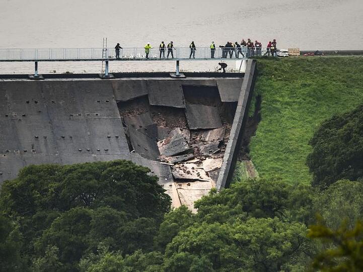 Menschen bilden über dem beschädigter Teil eines Staudamms am Toddbrook Reservoir nahe Whaley Bridge eine Menschenkette, um Sandsäcke auszulegen.