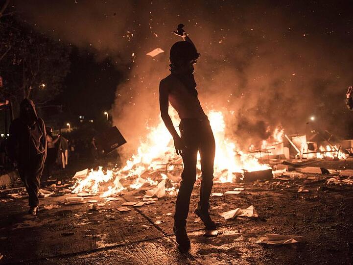 Demonstrant vor einer brennenden Barrikade.