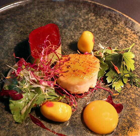 1. Gang: Jakobsmuschel, Spinat, Griechischer Joghurt, Hibiskus, Kumquat: Ein kleines Törtchen aus Joghurt, eine Mango-Sphäre, die außen fest, innen flüssig ist, gegarte Kumquats: Heimüllers Art, die verschiedensten Genüsse zu einem Gang zu vereinen, zeigt sich schon im ersten Gang deutlich - und köstlich. Der Silvaner &bdquo;Muschelkalk&ldquo; passt mit einer Spur Zitrus gut dazu.
