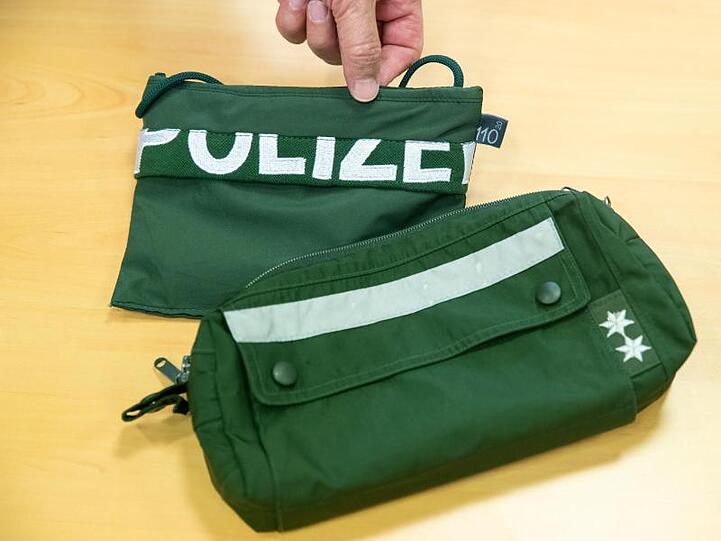 Ein Brustbeutel und eine Fahrrad-Lenkertasche gefertigt aus Stoffen alter Polizei-Uniformen liegen auf einem Tisch. Foto: Daniel Karmann