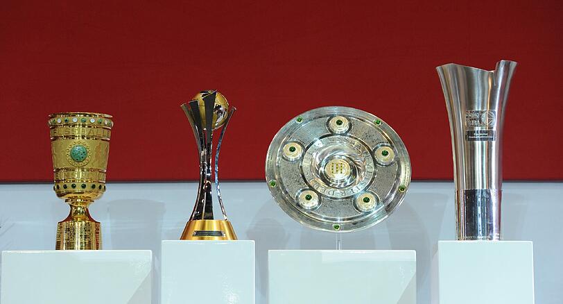 Im Trophäenschrank: das Double aus Meisterschaft und DFB-Pokal sowie der Fußball-Weltpokal und die Trophäe der Basketball-Meisterschaft.