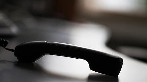 Ein Telefonhörer liegt auf einem Tisch.