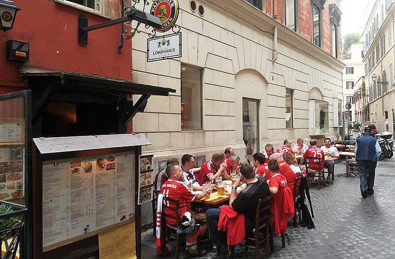 Gut 15 Bayern-Fans stärken sich am Dienstagmittag in einem Wirtshaus in Rom. Dass das "Löwenhaus" den Namen des Stadtrivalen 1860 beinhaltet, soll vor dem Kracher gegen AS Rom vergessen sein.