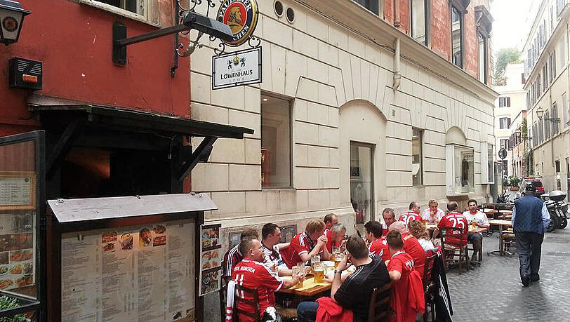 Gut 15 Bayern-Fans stärken sich am Dienstagmittag in einem Wirtshaus in Rom. Dass das "Löwenhaus" den Namen des Stadtrivalen 1860 beinhaltet, soll vor dem Kracher gegen AS Rom vergessen sein. Gut 15 Bayern-Fans stärken sich am Dienstagmittag in einem Wirtshaus in Rom. Dass das "Löwenhaus" den Namen des Stadtrivalen 1860 beinhaltet, soll vor dem Kracher gegen AS Rom vergessen sein.