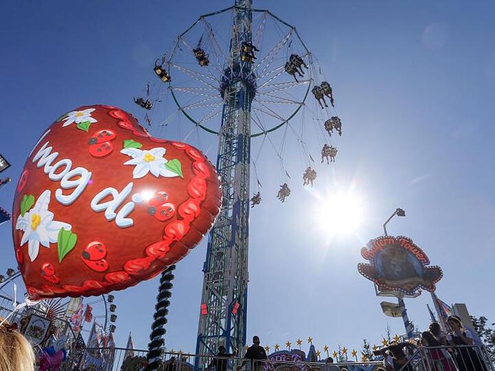 Hinter einem Luftballon mit der Aufschrift "I mog di" dreht sich das Fahrgeschäft "Bayern-Tower", ein Riesen-Kettenkarussell. Foto: Karl-Josef Hildenbrand