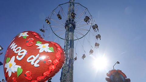 Hinter einem Luftballon mit der Aufschrift "I mog di" dreht sich das Fahrgeschäft "Bayern-Tower", ein Riesen-Kettenkarussell. Foto: Karl-Josef Hildenbrand