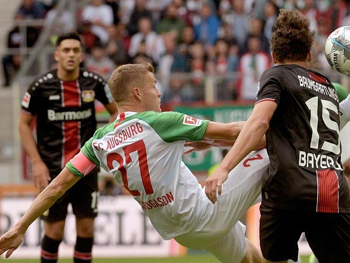 Augsburgs Alfred Finnbogason (M) macht es akrobatisch.