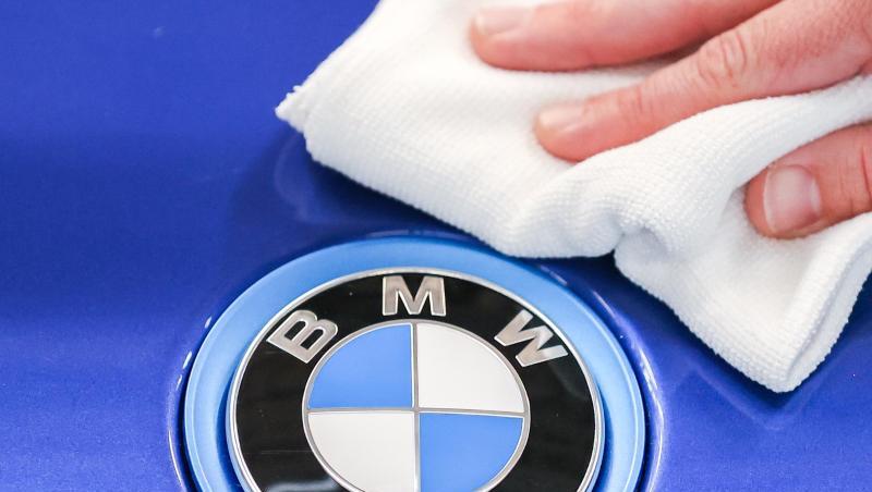 Ein Mitarbeiter von BMW poliert mit einem Tuch das Logo von einem BMW i8.