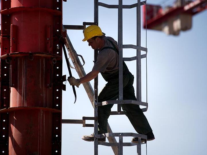Ein Arbeiter montiert an einem Kran. Foto: Alexander Heinl/Archivbild