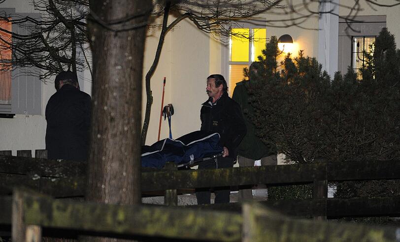 Zwei Bestatter tragen am Montag in Traunstein-Kotzing einen Sarg in Richtung Leichenwagen. Zuvor hatten Einsatzkräfte der Polizei eine 55-jährige Frau tot in ihrer Wohnung gefunden.