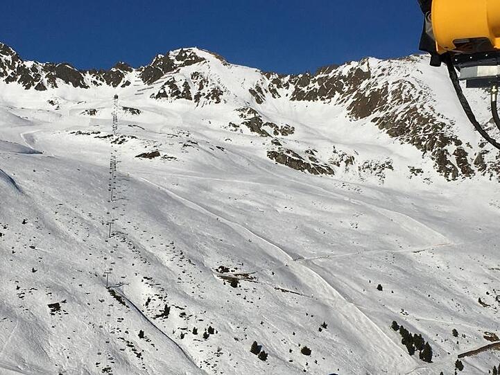 Ein Skifahrer und eine große Schneekanone im Skigebiet. Foto: Carsten Hoefer/dpa