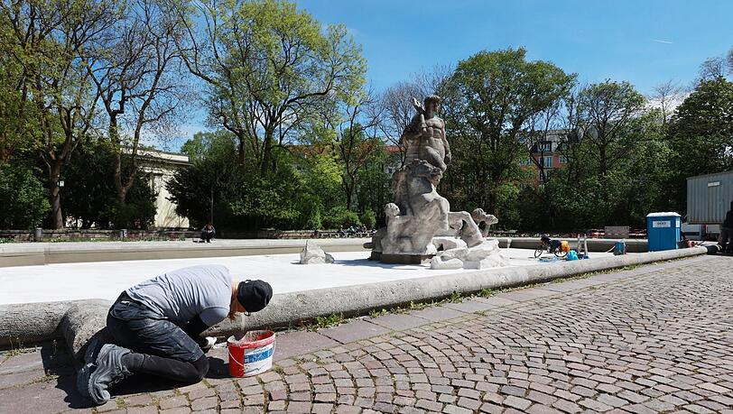 26. April: Alles blitzweiß, der ausgeleerte Neptunbrunnen wird frisch gereinigt, eine Steinmetzin arbeitet am steinernen Brunnenrand. 26. April: Alles blitzweiß, der ausgeleerte Neptunbrunnen wird frisch gereinigt, eine Steinmetzin arbeitet am steinernen Brunnenrand.