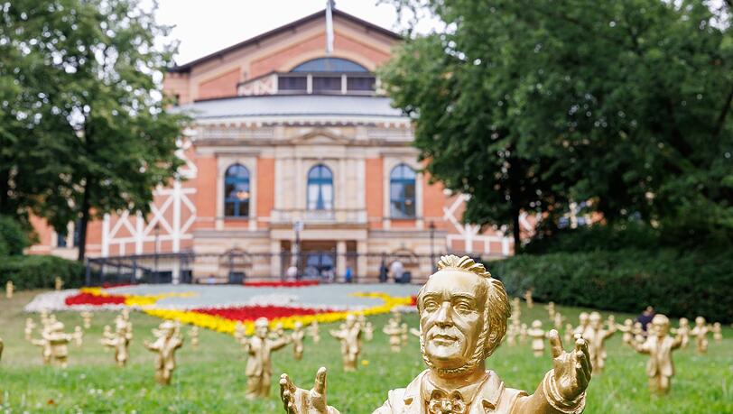 Goldfarbene Wagner-Figuren des Konzeptkünstler Ottmar Hörl stehen vor dem Festspielhaus.