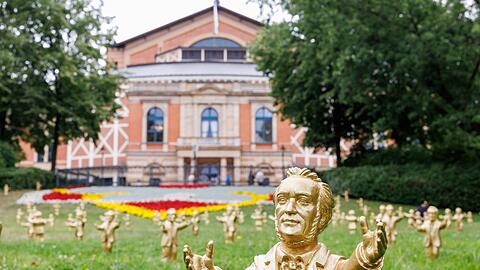 Goldfarbene Wagner-Figuren des Konzeptkünstler Ottmar Hörl stehen vor dem Festspielhaus.