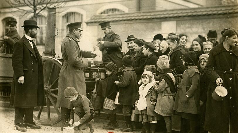 Eine mobile Suppenküche des DRK in München um 1920. Nach dem Ersten Weltkrieg verteilen Helfer kostenloses Essen an Bedürftige.
