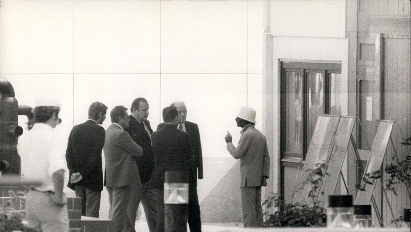 1972 im Olympiadorf: Einer der Geiselnehmer (mit weißem Hut) verhandelt mit Innenminister Dietrich Genscher (3. v. r.) und Polizeipräsident Manfred Schreiber (3. v. l.).
