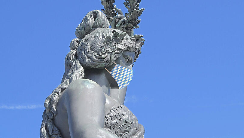 Die Bavaria setzt sich die Maske auf und schaut auf eine seltsam leere Theresienwiese.