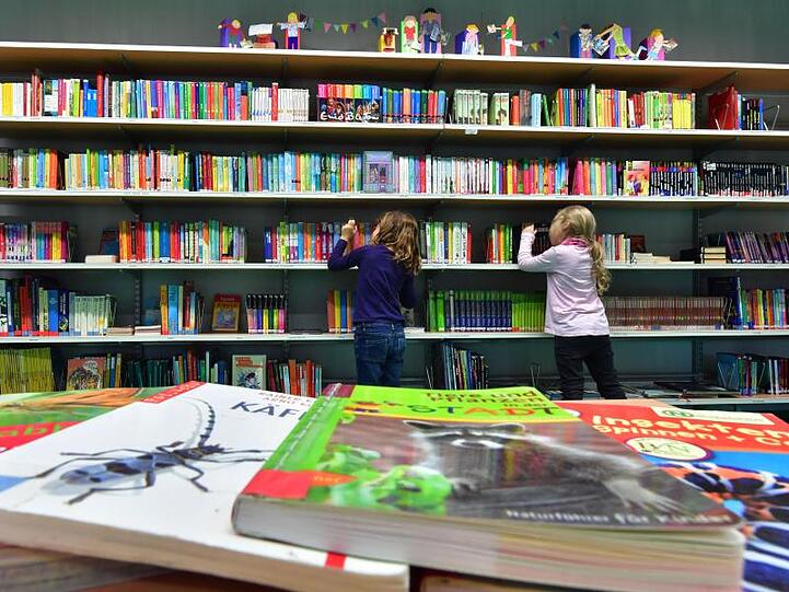 In einer Bibliothek suchen sich Kinder Bücher aus. Foto: Martin Schutt/Archivbild