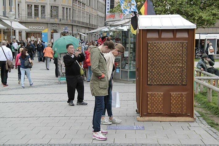 ...in der Fußgängerzone bleiben vor dem Häuschen mit dem braun-goldenen, an Louis Vuitton erinnernden Muster stehen.