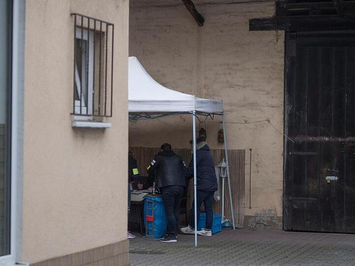 Beamte der Kriminalpolizei sichern im Hinterhof eines Hauses sichergestellte Asservate.