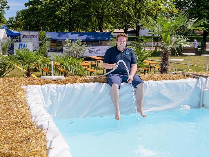 Florian Pöhlmann, Ortsvorsitzender der Jungen Union in Vaterstetten, lässt Wasser aus einem Schlauch in einen Strohballen-Pool laufen. Foto: Matthias Balk