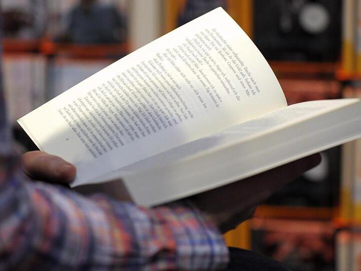 Eine Person hält ein aufgeschlagenes Buch in den Händen. Foto: Peter Endig/dpa-Zentralbild/dpa/Symbolbild