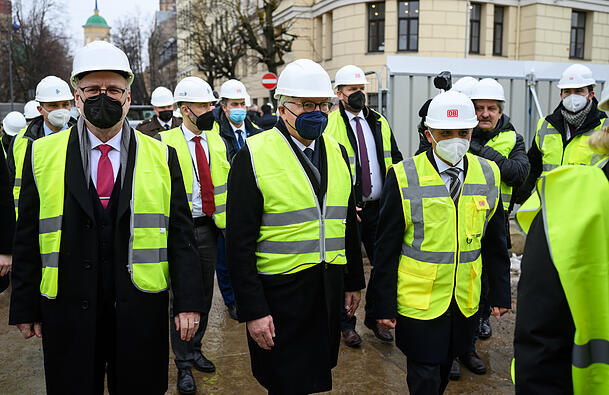 Auch bei diesem verz&ouml;gerten Megaprojekt war er schon zu Besuch: Bundespr&auml;sident Frank-Walter Steinmeier (M.) und Egils Levits (l.), damaliger Pr&auml;sident von Lettland, besuchen 2022 zusammen mit Burhan Erkan (vorne rechts), Gesch&auml;ftsf&uuml;hrer der DB Engineering & Consulting GmbH, eine Baustelle der Rail Baltica am Hauptbahnhof von Riga. Die Eisenbahnstrecke soll von Warschau (Polen) &uuml;ber die baltischen L&auml;nder Litauen, Lettland und Estland bis nach Helsinki (Finnland) f&uuml;hren.