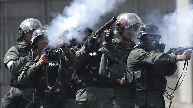 Sicherheitskräfte der Nationalgarde feuern in Caracas Tränengas in Richtung protestierender Demonstranten.