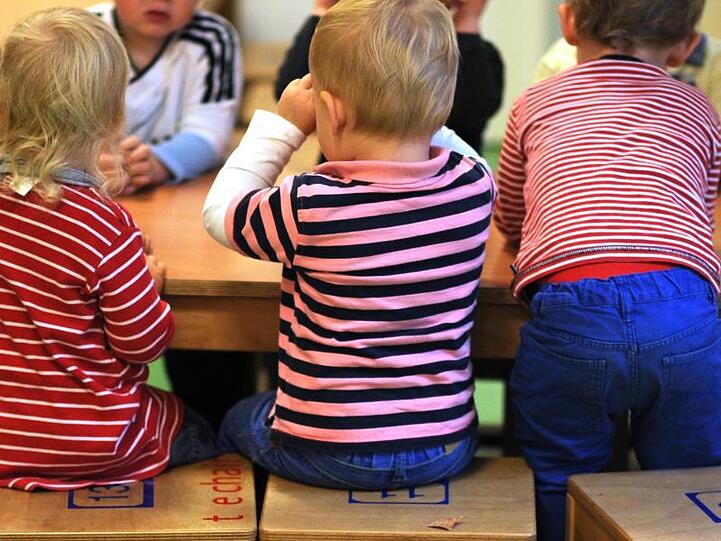 Kinder sitzen an einem Tisch. Foto: Julian Stratenschulte/dpa/Archivbild