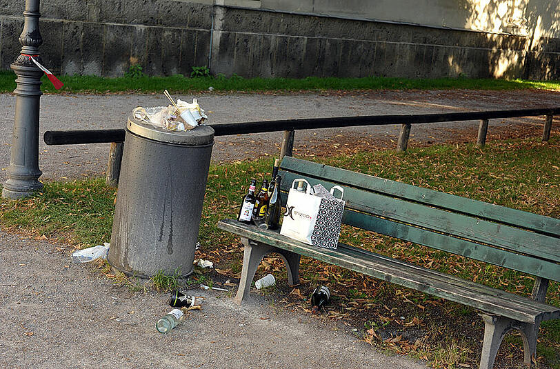 Leere Flaschen auf der Parkbank, Müll, der überquillt...