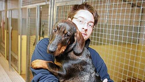 Tierpfleger Benni kuschelt mit Dackel-Mischling Langer. Tierpfleger Benni kuschelt mit Dackel-Mischling Langer.