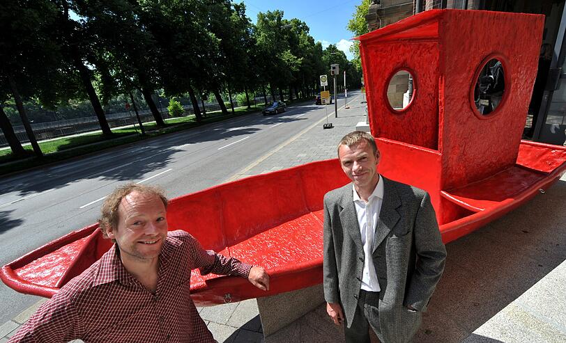 Die Künstler Thomas Huber (l) und Wolfgang Aichner stehen am Dienstag (24.05.2011) in München (Oberbayern) bei der Pk zum Kunstprojekt «Passage2011» vor ihrem roten selbstgebauten Boot das sie mit bloßen Händen über die Alpen ziehen wollen.