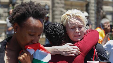 Unterschiedliche Hautfarbe, gleiche Gefühle: Zwei Frauen trauern in Kapstadt um Nelson Mandela.