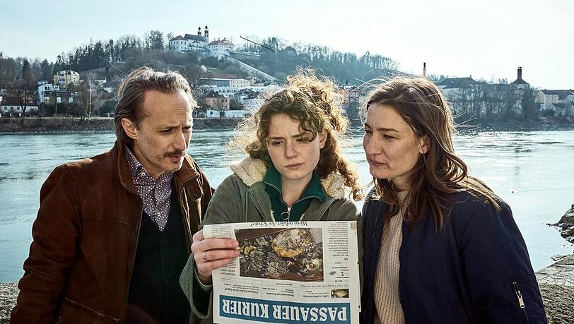 "Gier nach Gold. Ein Krimi aus Passau": Ferdinand Zankl (Michael Ostrowski), Mia Bader (Nadja Sabersky) und Frederike Bader (Marie Leuenberger) lesen interessiert Mias neuen Artikel in der Zeitung.