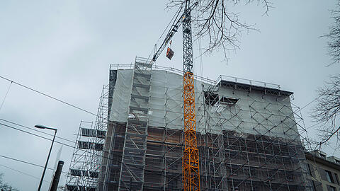 Der Geb&auml;udekomplex von der Leonrodstra&szlig;e aus. Ein gelber Kran beugt sich &uuml;ber das Haus.