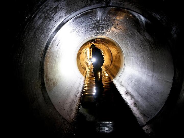 Ein Mitarbeiter schaut sich einen Teil eines Wasserkanales an. Foto: Ralf Hirschberger/dpa/Illustration