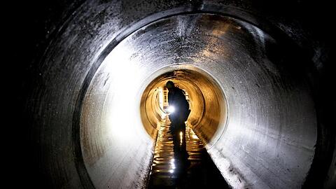 Ein Mitarbeiter schaut sich einen Teil eines Wasserkanales an. Foto: Ralf Hirschberger/dpa/Illustration