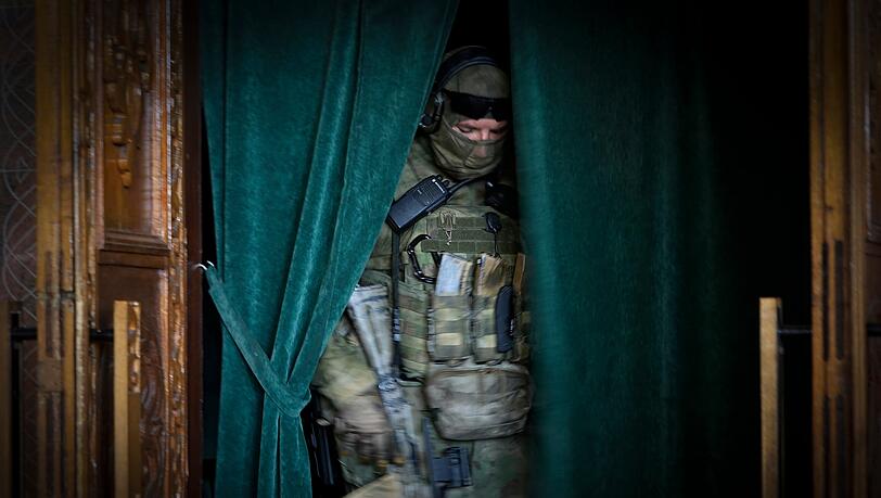 Mariupol: Ein russischer Soldat steht hinter einem Vorhang im Saal einer Philharmonie. Mariupol: Ein russischer Soldat steht hinter einem Vorhang im Saal einer Philharmonie.