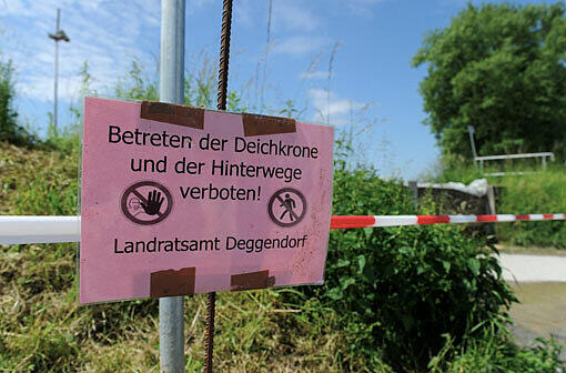 Ein Verbotsschild, das vor dem Betreten der Deichkrone warnt, steht in Metten bei Deggendorf am Rand des Deichs an einer Absperrung