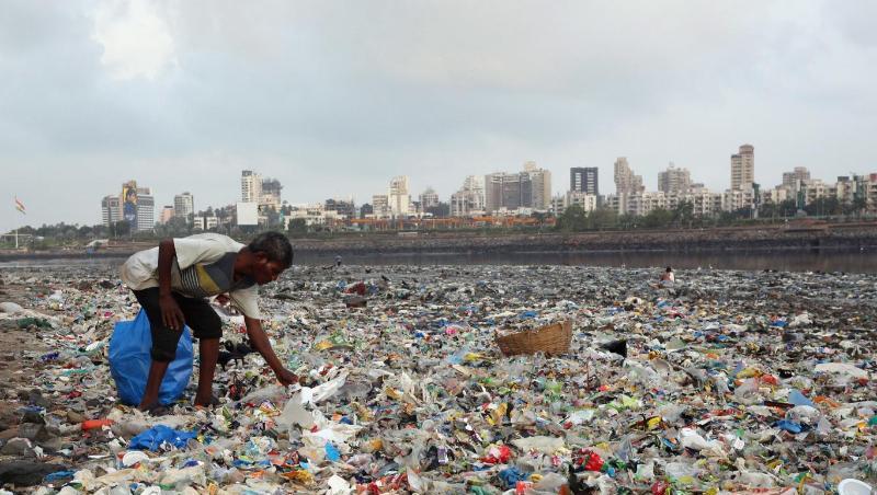 Ein Mann sammelt Plastik und andere wiederverwertbare Materialen an der von Plastiktüten und sonstigen Müll übersäten Küste vor Mumbai. Ein Mann sammelt Plastik und andere wiederverwertbare Materialen an der von Plastiktüten und sonstigen Müll übersäten Küste vor Mumbai.