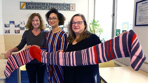 Sara Webers (M.) Mutter Claudia hat ein Jahr an einem Verspätungsschal gestrickt. Der wurde nun versteigert. Am Samstag hat die Übergabe in der Bahnhofsmission mit den Leiterinnen Bettina Spahn (l.) und Barbara Thoma stattgefunden.