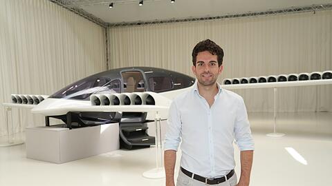 Daniel Wiegand vor seiner Erfindung: ein Flugtaxi mit 36-fachem elektrischem Düsentrieb. Der Prototyp des Lilium Jet im Hintergrund, der wie in einem Fotostudio mit weißen Vorhängen präsentiert wird, kommt der Endversion nahe.