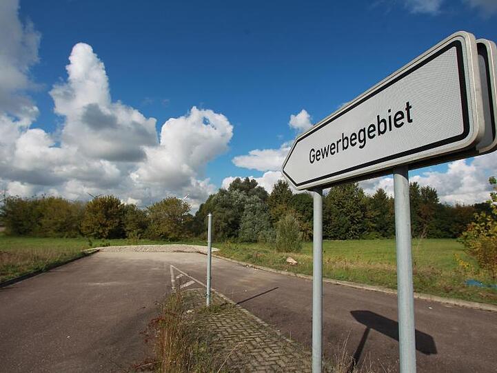 Ein Hinweisschild mit der Aufschrift "Gewerbegebiet" vor einer unbebauten Sackgasse. Foto: Jens Wolf/Archiv