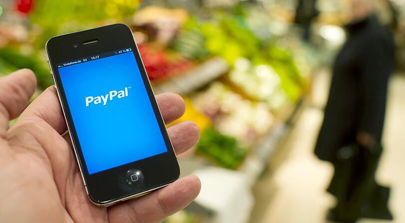 Der Startbildschirm der PayPal App ist in der Lebensmittelabteilung eines Warenhauses in Berlin auf dem Display eines Smartphones zu sehen. Kontaktloses Bezahlen an der Ladenkasse im Vorbeigehen oder mit einer App auf dem Handy - neue Bezahlverfahren sind im Kommen.