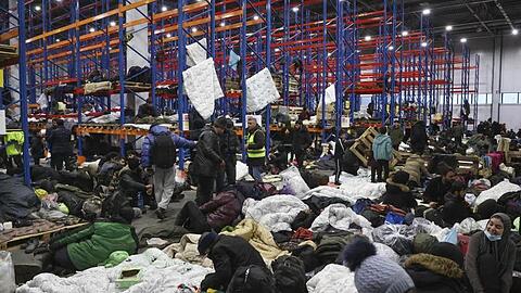 Migranten, die sich für die Nacht im Logistikzentrum am Kontrollpunkt "Kuznica" an der belarussisch-polnischen Grenze einrichten.
