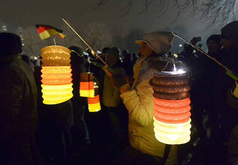 Teilnehmer der islamkritischen Pegida-Bewegung halten am 05.01.2015 Laternen in den Farben schwarz-rot-gold bei einer Kundgebung in Dresden (Sachsen). Die Pegida hat zu einer erneuten Demonstration in Sachsens Landeshauptstadt aufgerufen.