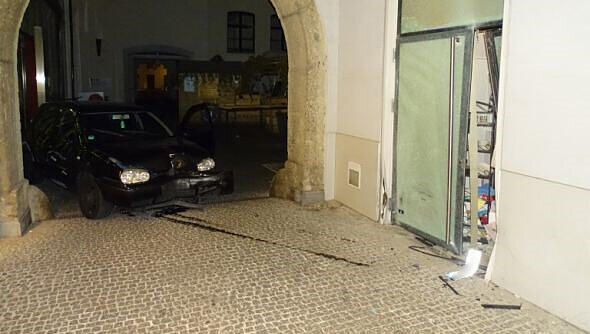 Die Tür ist kaputt, daneben ist das Auto zu sehen, mit dem die Einbrecher in den Laden fuhren.
